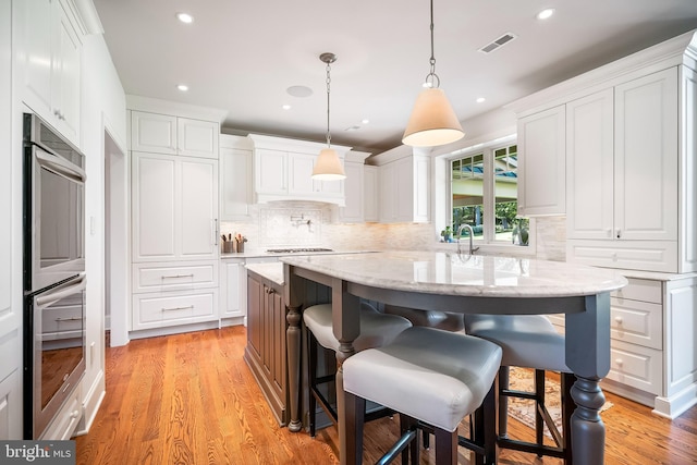 kitchen featuring white cabinetry, light wood-type flooring, and hanging light fixtures