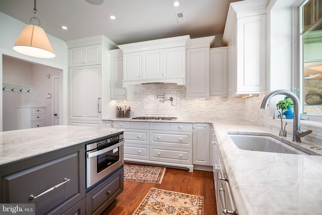 kitchen with white cabinets, light stone countertops, sink, and pendant lighting