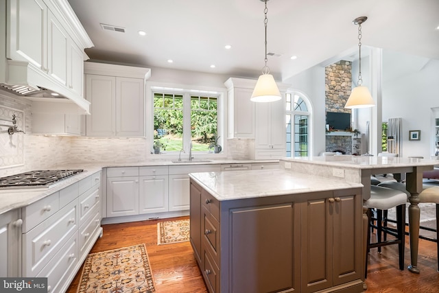 kitchen featuring dark hardwood / wood-style floors, pendant lighting, a kitchen island, and white cabinets