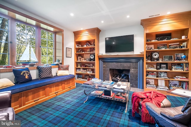 living room featuring built in features and a premium fireplace