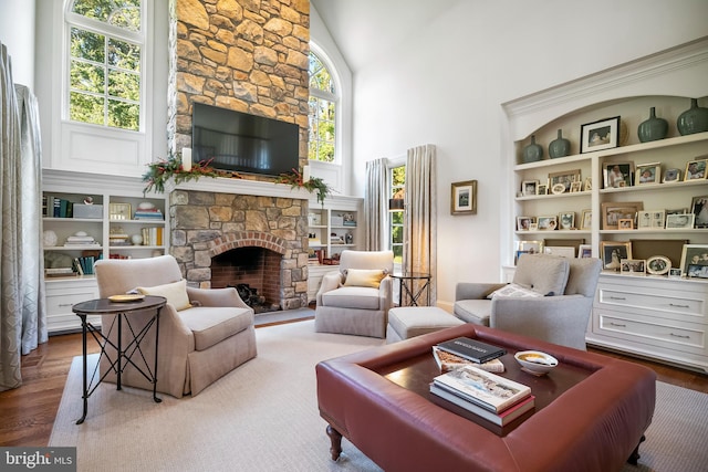 living room featuring a stone fireplace, high vaulted ceiling, and wood-type flooring