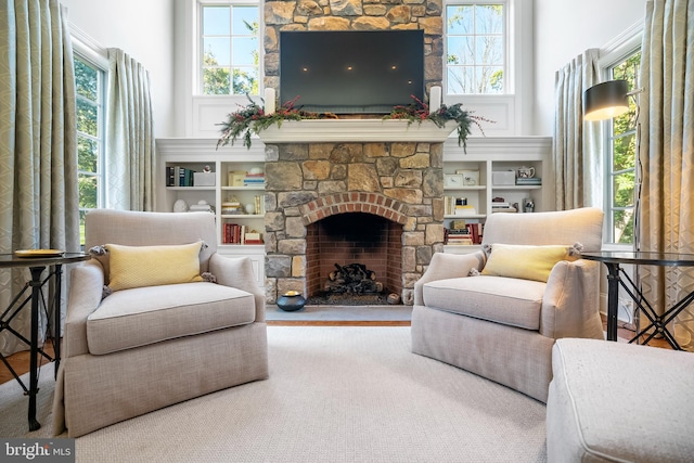 living room featuring a stone fireplace, wood-type flooring, and built in features