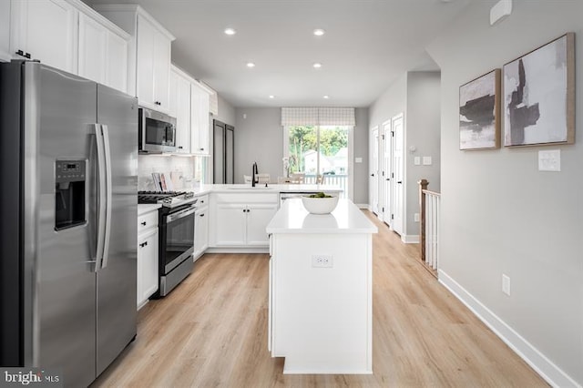 kitchen featuring decorative backsplash, light hardwood / wood-style flooring, stainless steel appliances, sink, and white cabinetry