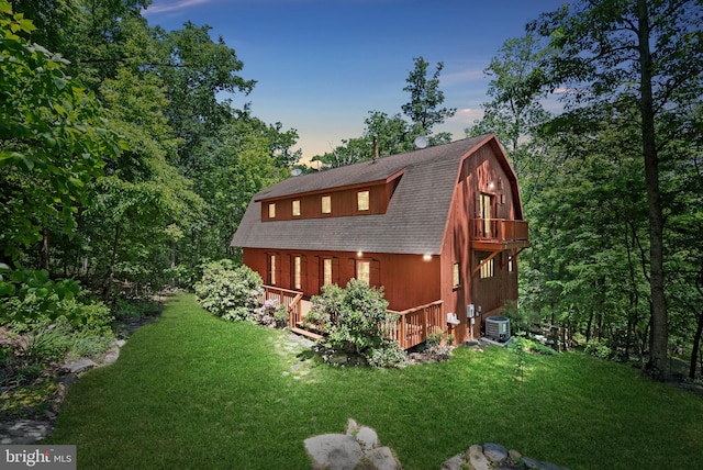 property exterior at dusk with a lawn, central air condition unit, and a deck