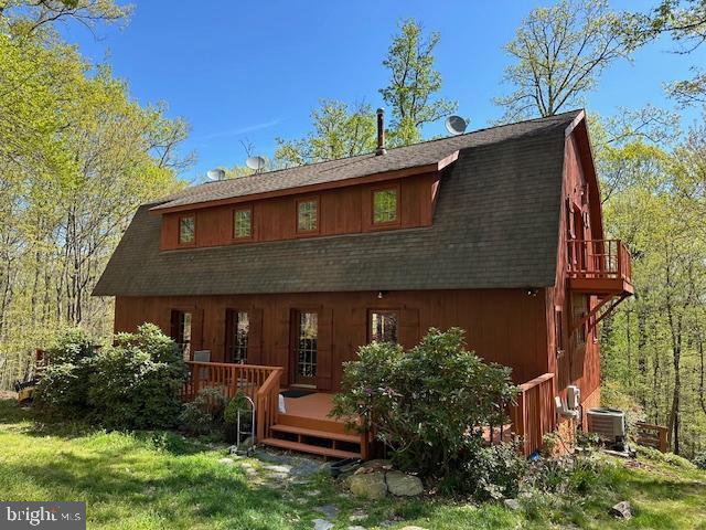 rear view of property with cooling unit, a deck, and a lawn