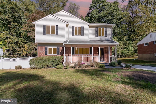 view of front of home with covered porch and a lawn