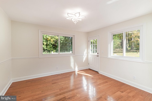 unfurnished room with light hardwood / wood-style floors and a notable chandelier