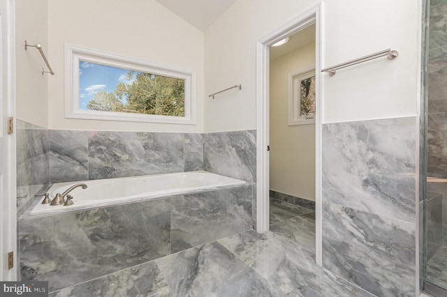 bathroom with vaulted ceiling and tiled tub