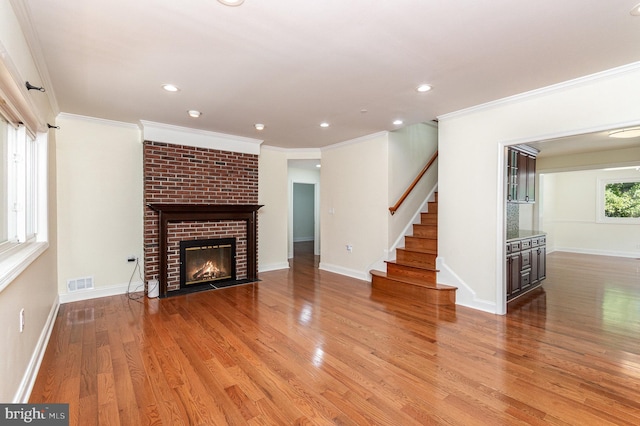 unfurnished living room featuring ornamental molding, a fireplace, and hardwood / wood-style flooring