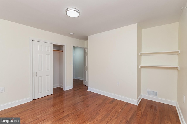 unfurnished bedroom with a closet and hardwood / wood-style flooring