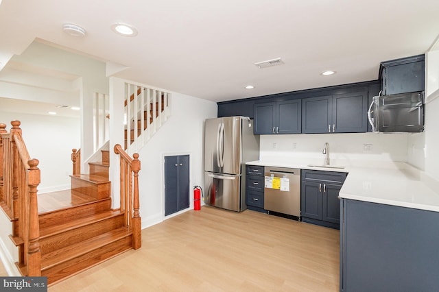 kitchen featuring light hardwood / wood-style floors, stainless steel appliances, sink, and blue cabinets