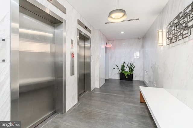 hallway featuring tile walls and elevator