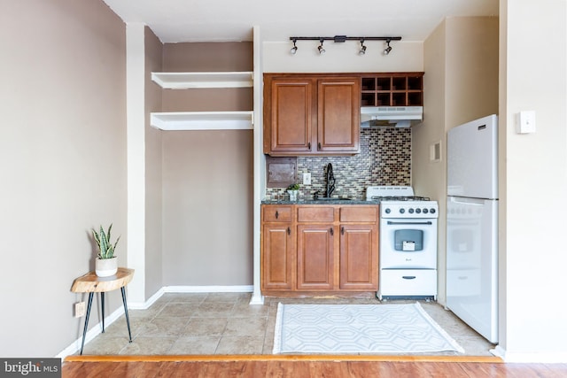 kitchen featuring tasteful backsplash, sink, light tile patterned floors, and white appliances