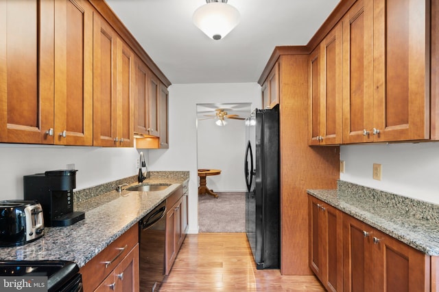 kitchen with light stone countertops, black appliances, sink, light hardwood / wood-style floors, and ceiling fan