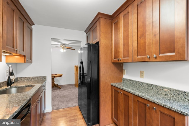 kitchen featuring light hardwood / wood-style floors, light stone countertops, sink, and black refrigerator