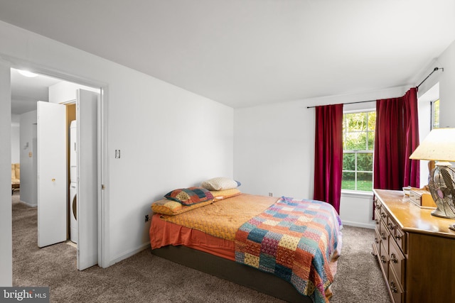 bedroom featuring stacked washer / dryer and light colored carpet