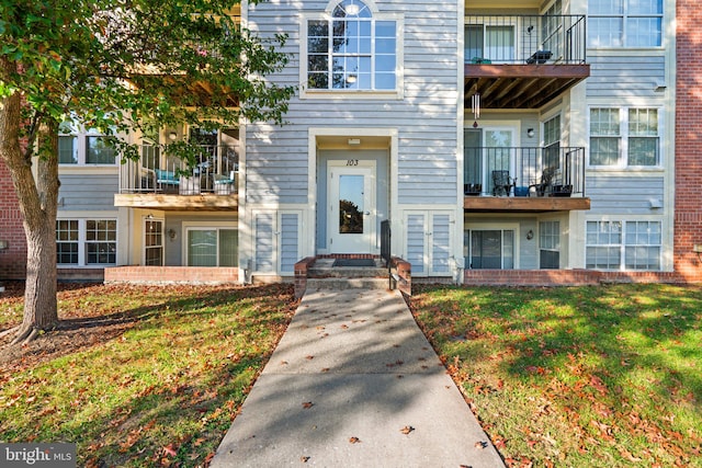 doorway to property with a balcony and a yard