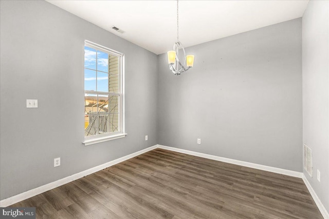 unfurnished room featuring a notable chandelier and dark hardwood / wood-style floors