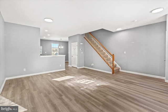 unfurnished living room with wood-type flooring and an inviting chandelier