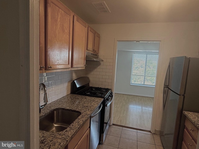 kitchen with light hardwood / wood-style flooring, stainless steel appliances, sink, and light stone counters