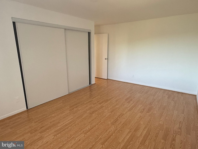 unfurnished bedroom with light hardwood / wood-style flooring and a closet