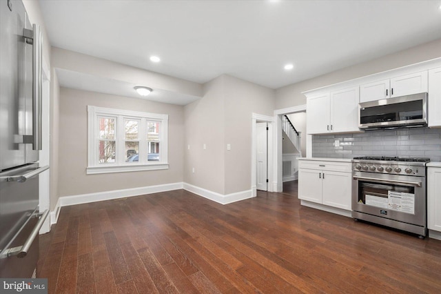 kitchen featuring high quality appliances, backsplash, white cabinetry, and dark wood-type flooring