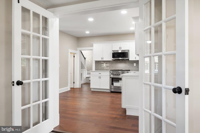 kitchen with decorative backsplash, white cabinets, stainless steel appliances, and dark hardwood / wood-style flooring