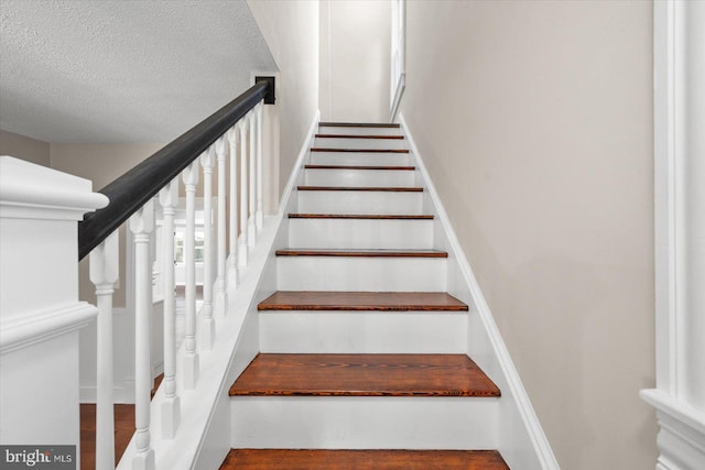 stairs featuring a textured ceiling and hardwood / wood-style flooring