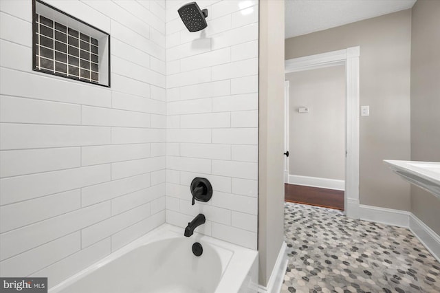 bathroom with tile patterned floors, tiled shower / bath combo, and a textured ceiling