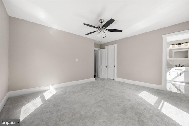 unfurnished bedroom featuring light colored carpet, connected bathroom, and ceiling fan