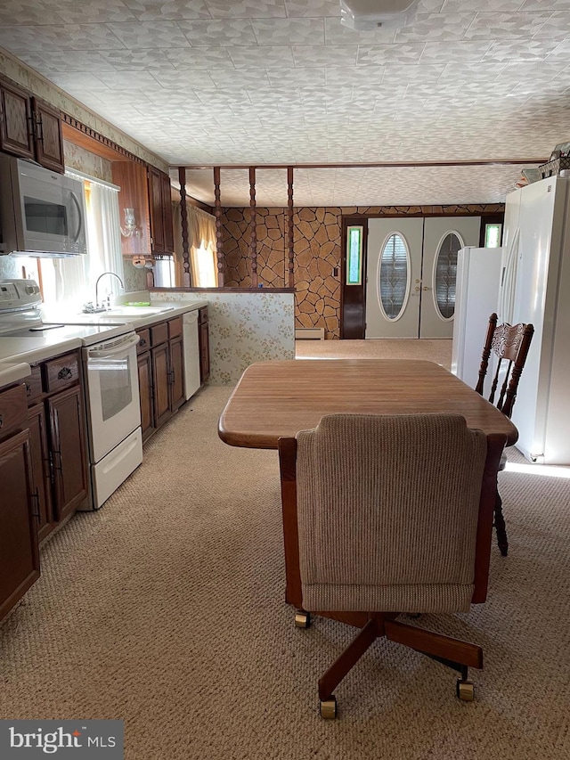 kitchen with sink, a textured ceiling, light colored carpet, and white appliances