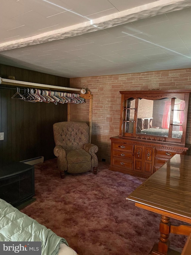 carpeted bedroom with brick wall, a baseboard heating unit, and wood walls