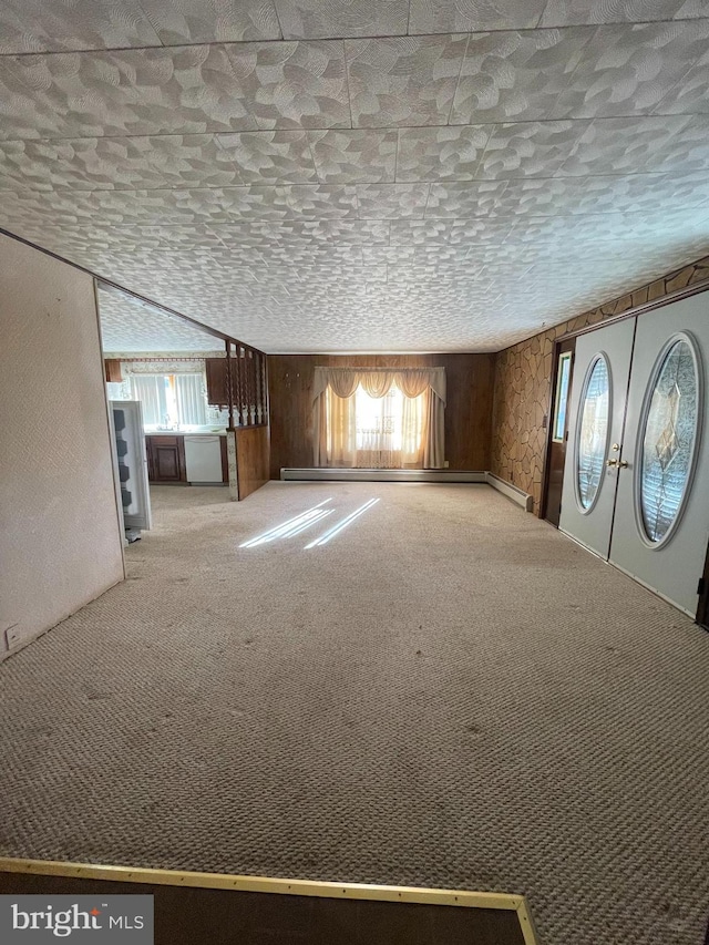 interior space with french doors, carpet flooring, a textured ceiling, and wooden walls