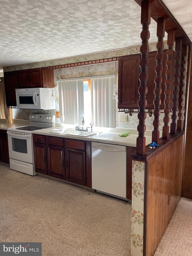 kitchen featuring white appliances, a textured ceiling, sink, and light colored carpet