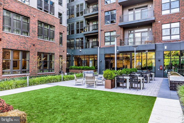 back of property featuring a patio, a lawn, and a balcony