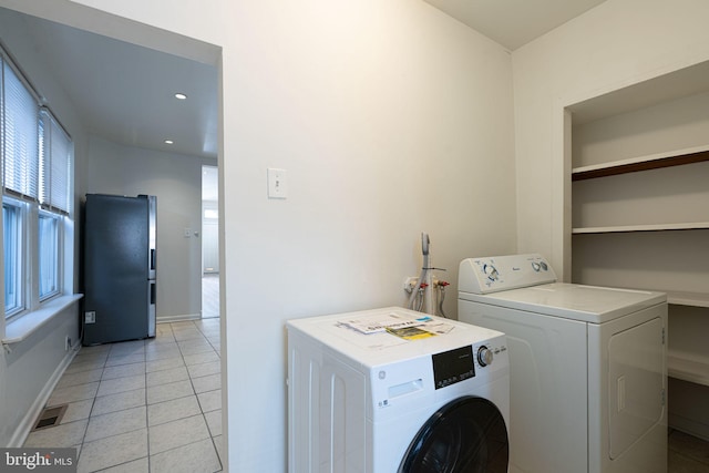 laundry area with independent washer and dryer and light tile patterned flooring