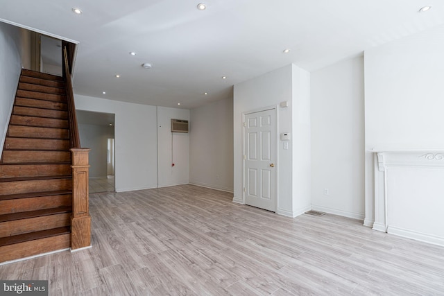 unfurnished living room with light hardwood / wood-style flooring and a wall mounted air conditioner