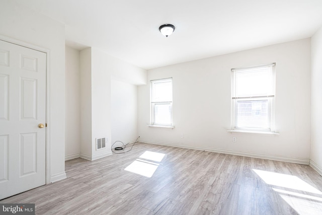 empty room with light wood-type flooring and plenty of natural light