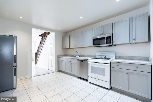 kitchen with gray cabinets, sink, appliances with stainless steel finishes, and light tile patterned floors