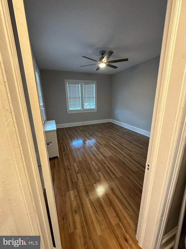 empty room with ceiling fan and dark hardwood / wood-style flooring