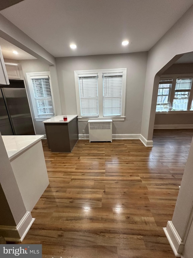 interior space with white cabinetry, stainless steel refrigerator, radiator heating unit, and dark hardwood / wood-style floors