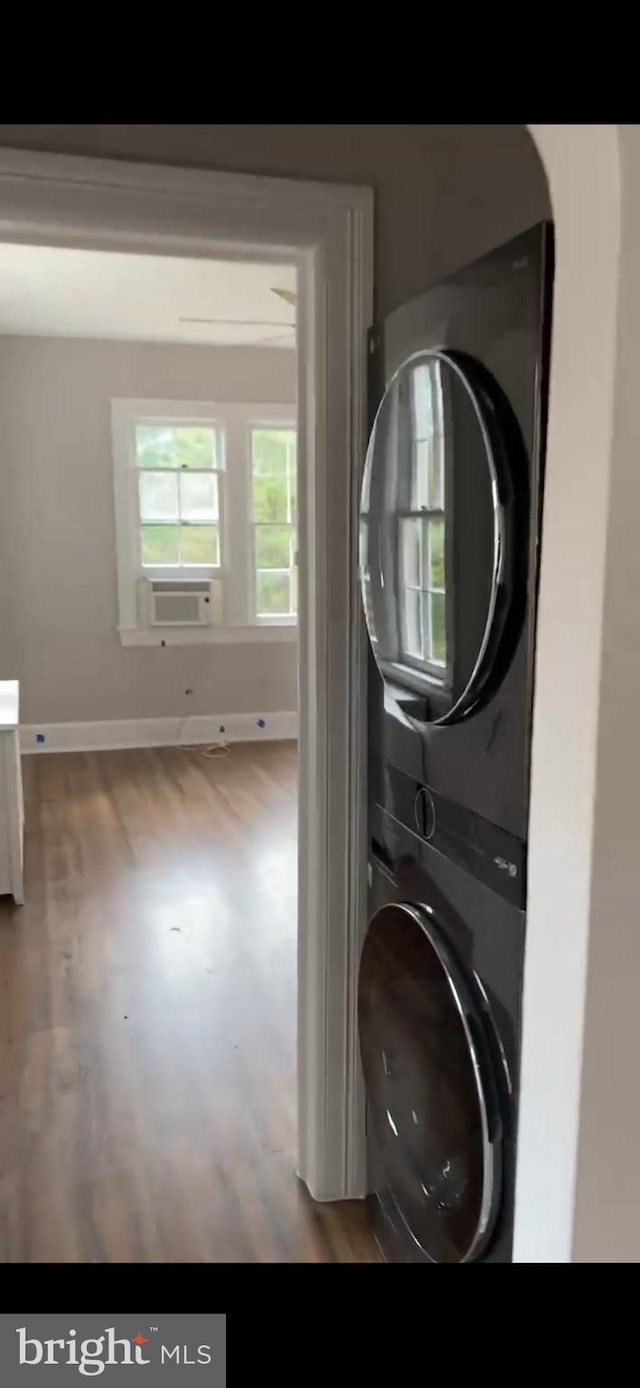 clothes washing area featuring hardwood / wood-style flooring and stacked washing maching and dryer