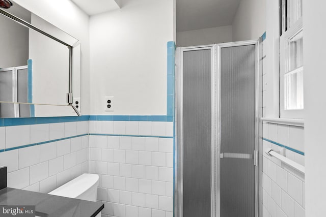 bathroom with a shower with door, tile walls, and toilet