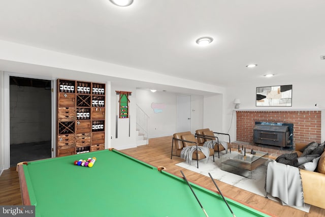 game room with pool table, hardwood / wood-style flooring, and a wood stove