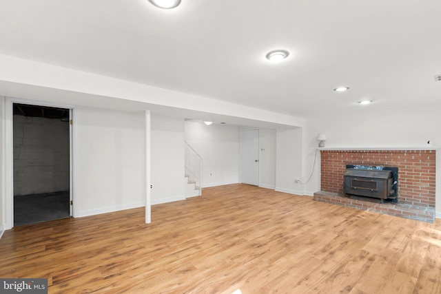 basement featuring light hardwood / wood-style floors and a wood stove