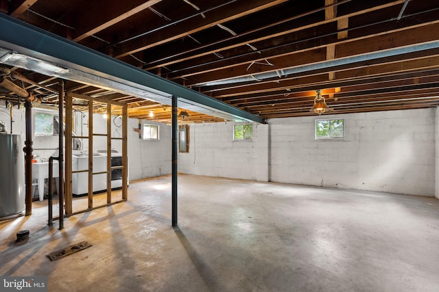 basement with gas water heater, electric panel, and a healthy amount of sunlight