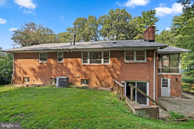 back of property featuring a patio, a sunroom, a lawn, and central AC unit