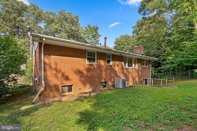 rear view of house featuring central AC unit and a lawn