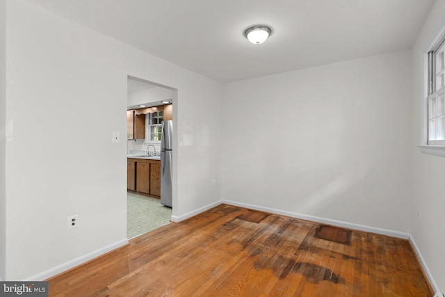 unfurnished room with sink, hardwood / wood-style flooring, and a healthy amount of sunlight