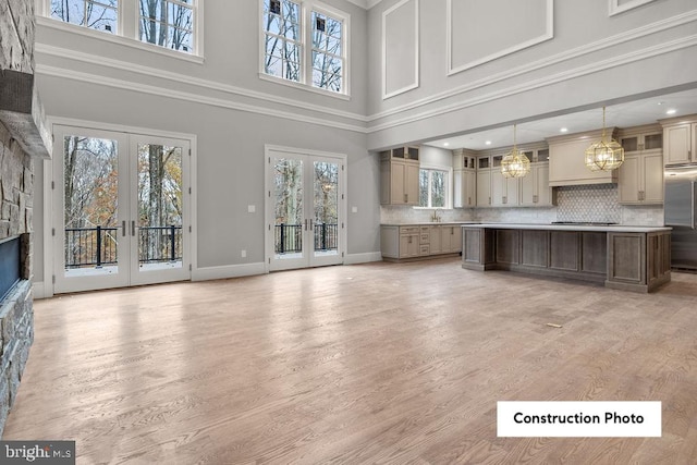 unfurnished living room featuring french doors, a towering ceiling, and plenty of natural light